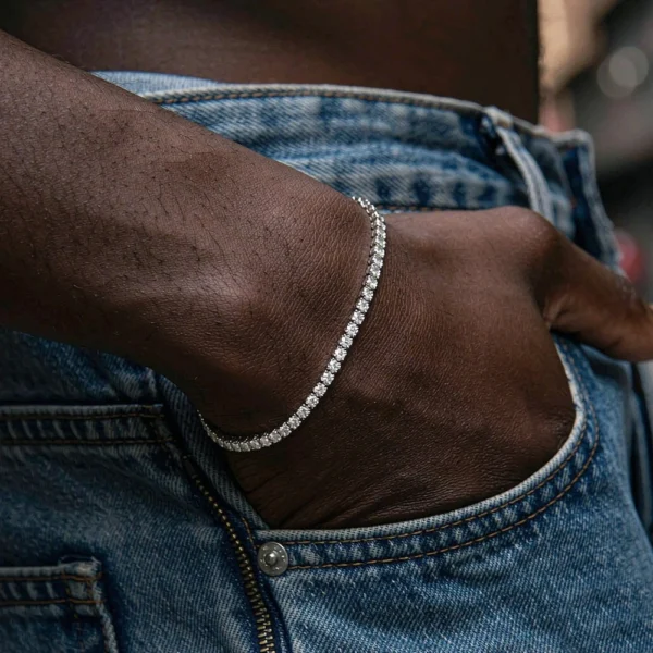 Close-up of a 3mm 14K gold color moissanite tennis bracelet on a woman’s wrist with hip hop streetwear styling.