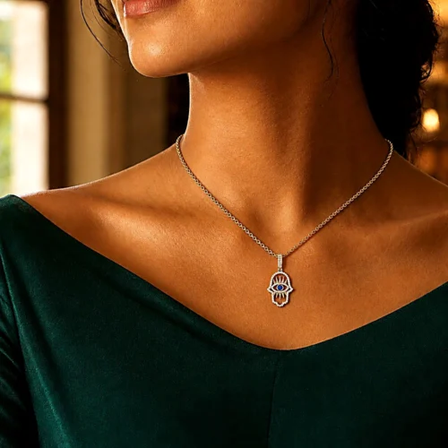 Woman wearing gold Hamsa Hand Evil Eye pendant necklace, 14K gold plated with micro-pavé stones.