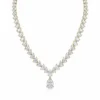 Woman wearing silver moissanite pear necklace in a bright interior - gala dinner jewelry